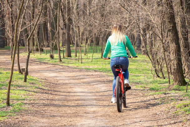 Дівчинка їде на електричному велосипеді в весняному лісі в Україні в місті Дніпро, на відкритому повітрі відпочинок - Фото, зображення