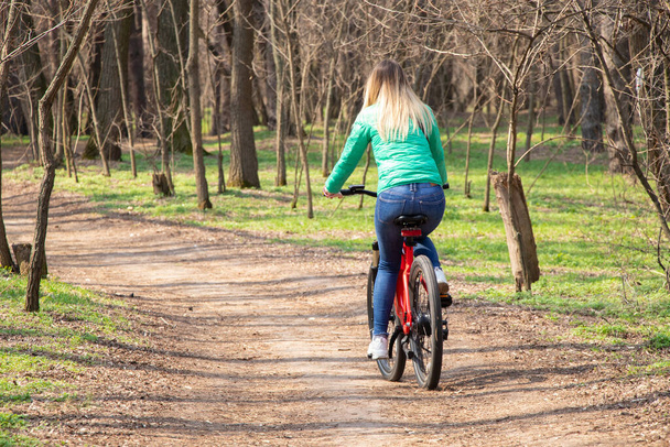 menina monta uma bicicleta elétrica na floresta de primavera na Ucrânia, na cidade de Dnipro, recreação ao ar livre - Foto, Imagem