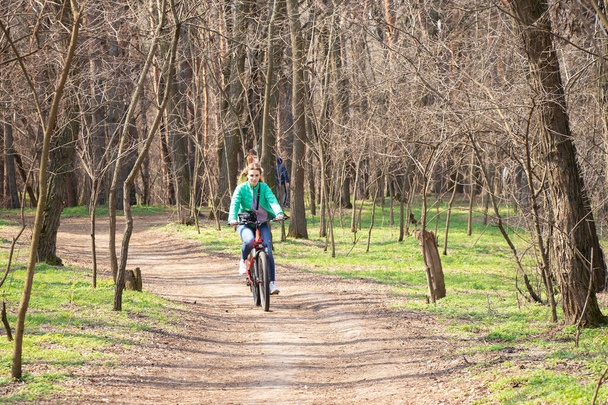 fille monte un vélo électrique dans la forêt de printemps en Ukraine dans la ville de Dnipro, loisirs de plein air - Photo, image
