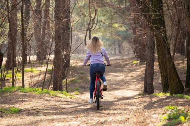 girl rides an electric bike in the spring forest in Ukraine in the city of Dnipro, outdoor recreation - Zdjęcie, obraz