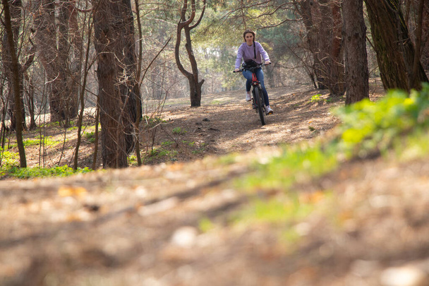 девушка ездит на электрическом велосипеде в весеннем лесу Украины в городе Днепр, на открытом воздухе отдыха - Фото, изображение