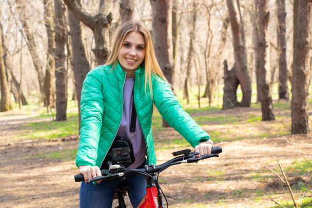 dziewczyna jeździ na rowerze elektrycznym w wiosennym lesie na Ukrainie w mieście Dnipro, rekreacji na świeżym powietrzu - Zdjęcie, obraz
