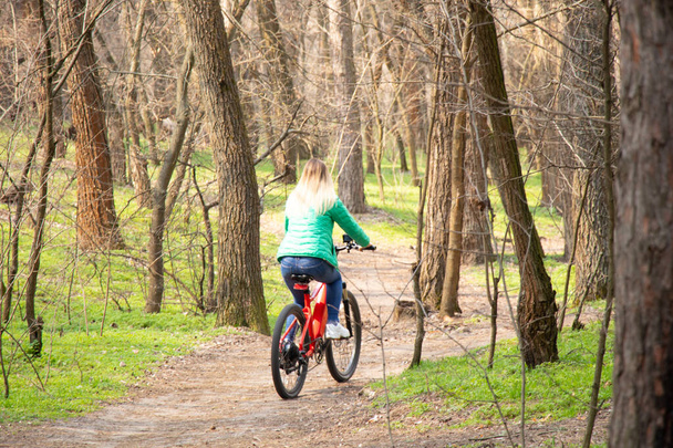 fille monte un vélo électrique dans la forêt de printemps en Ukraine dans la ville de Dnipro, loisirs de plein air - Photo, image