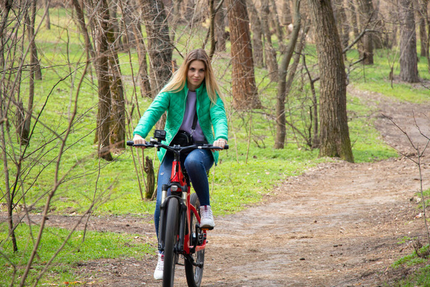 dziewczyna jeździ na rowerze elektrycznym w wiosennym lesie na Ukrainie w mieście Dnipro, rekreacji na świeżym powietrzu - Zdjęcie, obraz