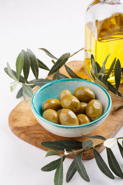 Olives vertes entières dans un bol sur une table blanche. Gros plan. - Photo, image