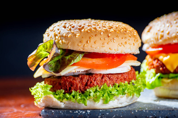Sabrosa comida vegetariana, hamburguesas caseras de queso hechas de carne de soja a base de plantas con queso, cebolla, lechuga verde y tomates de cerca - Foto, Imagen