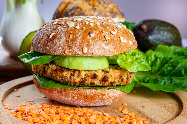 Tasty vegetarian healthy green food, homemade burgers made from orange lentils legumes with green lettuce and fresh ripe avocado - Fotoğraf, Görsel