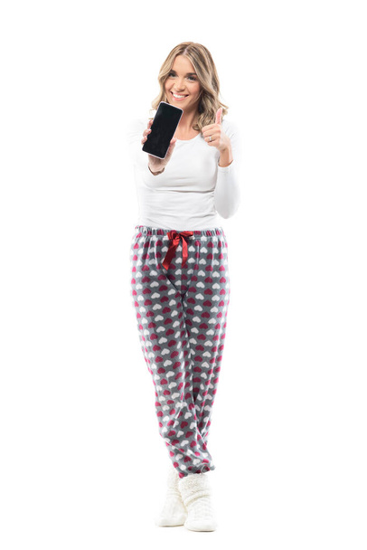 Cheerful excited young woman in home wear clothes showing blank smart phone screen at camera. Full body length isolated on white background. - Photo, Image