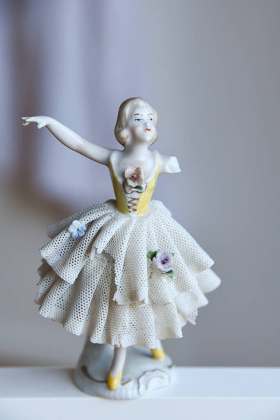 Bela figura de bailarina de porcelana vintage antiga com braço perdido quebrado dançando em vestido de balé de renda com detalhes florais. Boneca de porcelana brilhante isolado em fundo neutro com espaço de cópia vazio. - Foto, Imagem