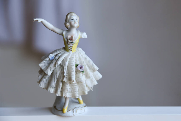 Hermosa figura antigua bailarina de porcelana vintage con brazo roto bailando en vestido de ballet de encaje con detalles florales. Muñeca de porcelana brillante aislada sobre fondo neutro con espacio de copia vacío. - Foto, Imagen