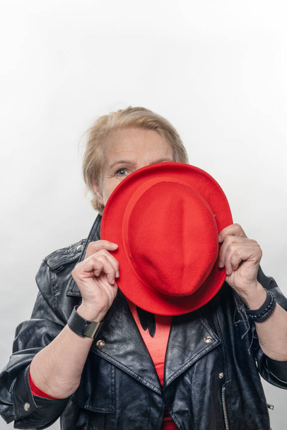 Κομψή γυναίκα στην ηλικία, με κόκκινο καπέλο και κόκκινη φόρμα. - Φωτογραφία, εικόνα