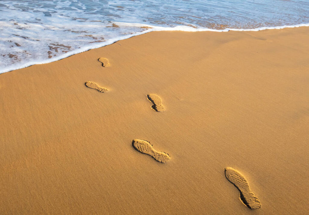 Huellas humanas en una playa de arena que conduce a la costa del océano Atlántico - Foto, Imagen