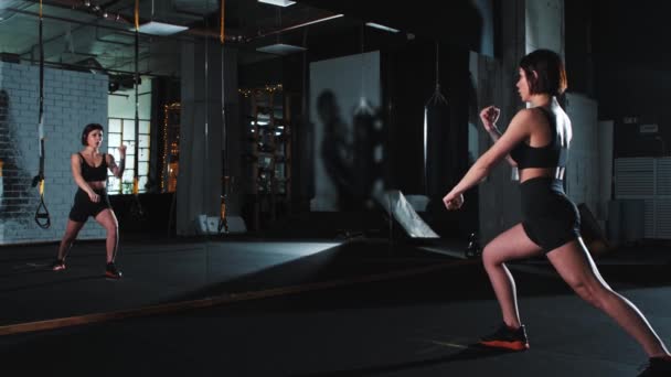 Een sterke getatoeëerde vrouw die karate traint beweegt voor een spiegel - Video