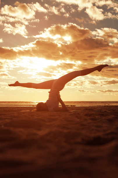 jonge mooie slanke vrouw silhouet praktijken yoga op de beac - Foto, afbeelding