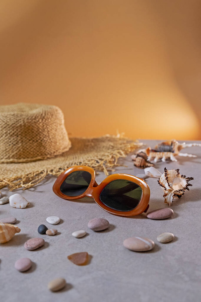 Verão, férias, viagens e turismo conceito - chapéu de palha feminino e óculos de sol jazem na areia da praia. Acessórios de verão de viagem com espaço de cópia, flat lay. Conceito de planeamento de viagens - Foto, Imagem