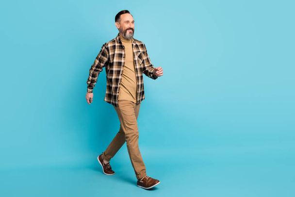 Full body photo of mature positive man walking into copy space isolated over blue color background - Valokuva, kuva