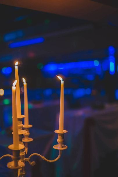 A vertical shot of a candlestick with many candles on a blurred background - Zdjęcie, obraz