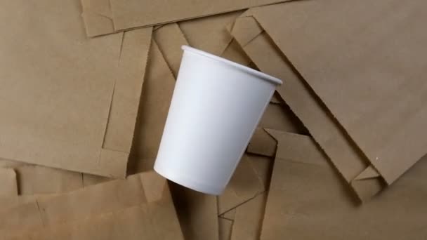 Paquete de papel vacío, embalaje biodegradable desechable ecológico para mercancías y taza de papel vacía. Rota en círculo. Fondo ecológico. Vista superior. Primer plano. - Metraje, vídeo
