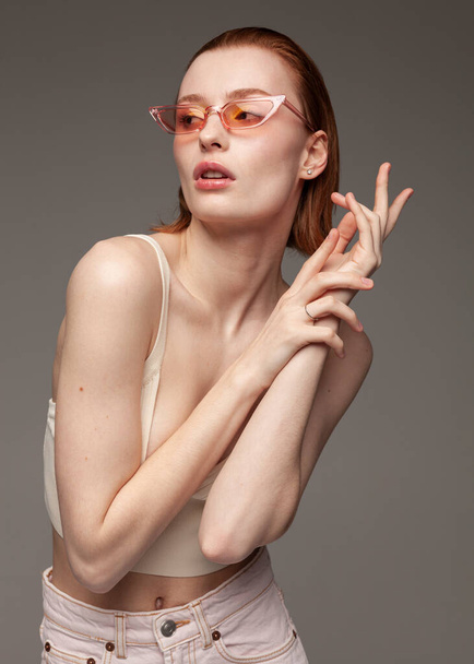 beautiful redhead girl in pink glasses on a dark background - Foto, Imagem