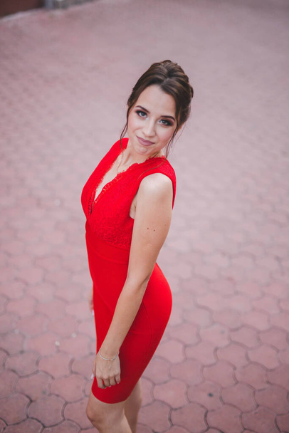 A high-angle shot of a sexy Caucasian lady wearing a red dress and posing outdoors - Fotoğraf, Görsel