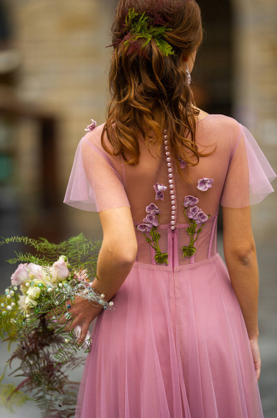 Morsian vaaleanpunaisessa mekossa kukkakimpulla seisoo Firenzen vanhan kaupungin keskustassa Italiassa.. - Valokuva, kuva