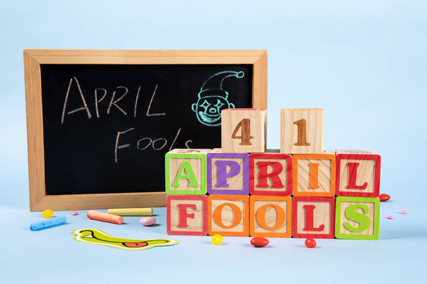 A closeup of a board with an "April Fools Day" message on a colorful party background - Foto, imagen