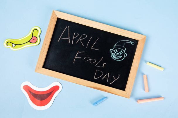 A top view of "April Fools Day" text written on a blackboard with funny faces - 写真・画像