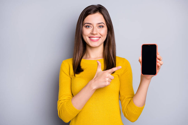 Portrait of pretty content cheerful girl holding in hand demonstrating gadget advert isolated over grey color background - Φωτογραφία, εικόνα