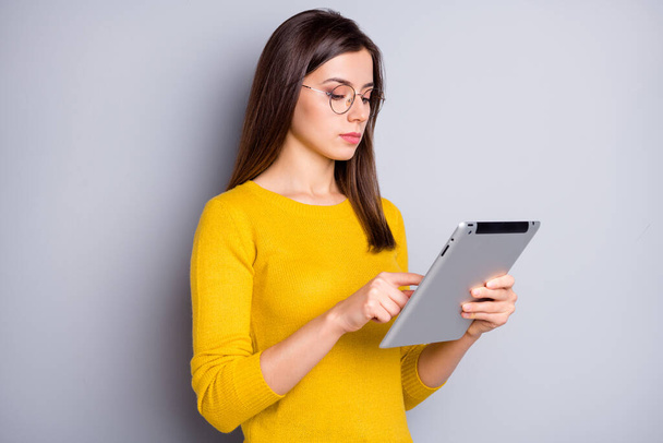 Profile side view portrait of lovely focused girl holding in hands using tablet searching information isolated over grey color background - Φωτογραφία, εικόνα