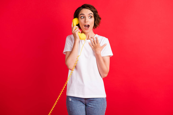 Portrait of lovely amazed cheerful girl talking on phone discussing news isolated over bright red color background - Foto, Bild