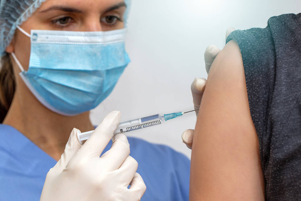 Nurse in surgical mask vaccinating person against viruses - Fotó, kép