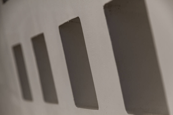 Detail quadratischer Löcher an einer grauen Betonwand - Foto, Bild