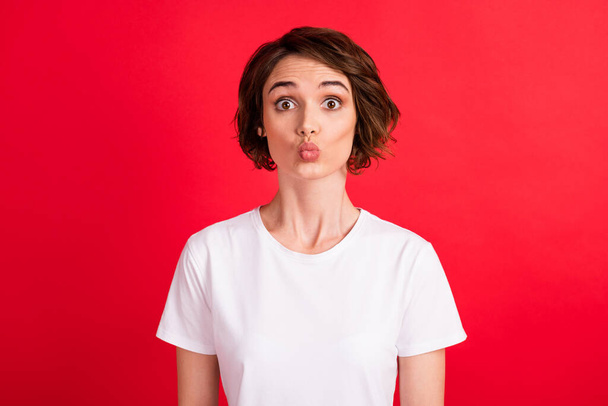 Portrait of attractive funny girlish girl sending air kiss isolated over bright red color background - Foto, Imagem