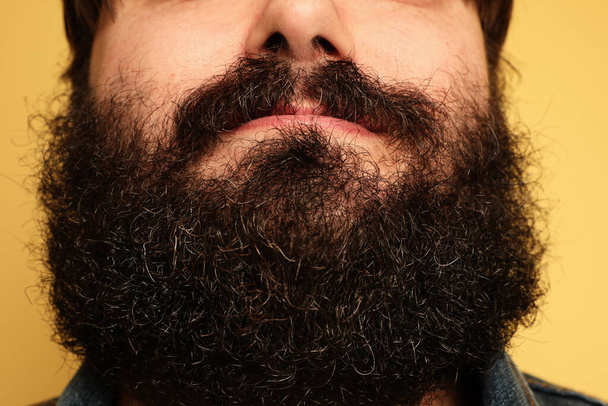 Close-up portrait of large bearded man on yellow background.  - Φωτογραφία, εικόνα