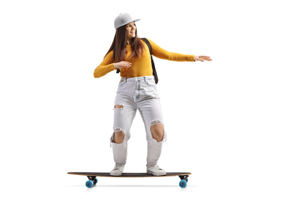 Full length shot of a cool female skater riding a longboard isolated on white background     - Foto, Imagem