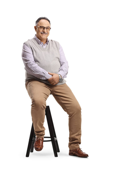 Corpulent mature man sitting on a high chair isolated on white background - Photo, Image