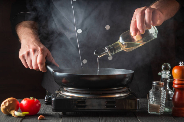 The chef adds olive oil to the pan while cooking. Working environment on the restaurant kitchen table - Photo, image