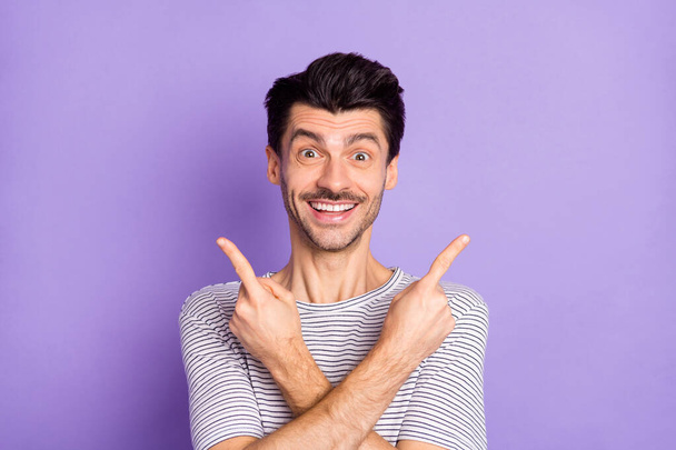 Photo of funny adviser guy direct fingers two empty spaces white smile wear striped t-shirt isolated purple background - Foto, afbeelding