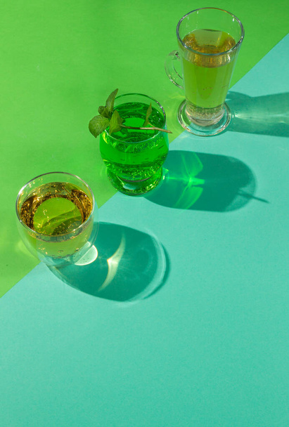 The concept of healthy natural lemonades, with elderberry, tarragon and kombucha. Refreshing cocktails with natural ingredients. On a colored background, close-up, hard shadows - Foto, afbeelding