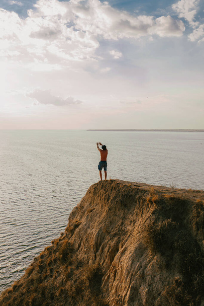 a man stands with his hands up on a hill by the sea - Photo, Image