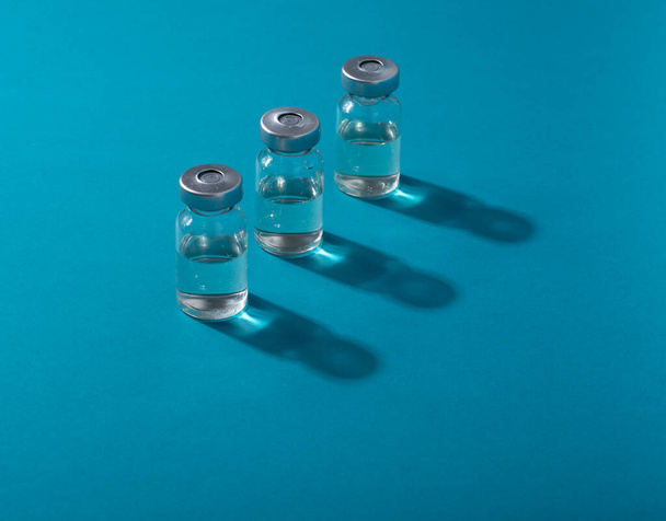 Ampollas transparentes, frascos con medicamentos o vacunas sobre fondo azul. Lugar para el texto. Copiar espacio. - Foto, Imagen