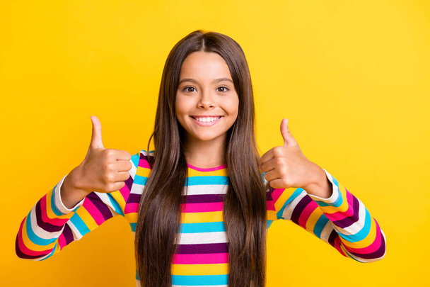 Photo of little girl raise two thumbs up toothy shiny smile wear striped shirt isolated yellow color background - Fotoğraf, Görsel