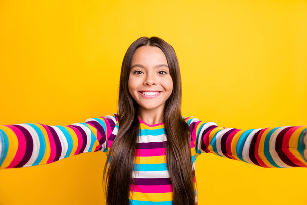 Photo of little girl make selfie look camera cheerful shiny smile wear striped shirt isolated yellow color background - Foto, afbeelding