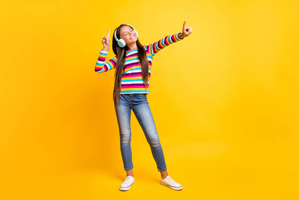 Full length body size photo of schoolgirl listens to music with headphones smiling dancing isolated on bright yellow color background - Foto, afbeelding