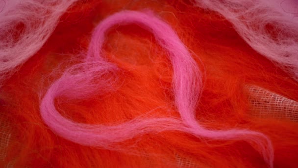 Coeur rose fait de laine est disposée sur une laine rouge - Séquence, vidéo