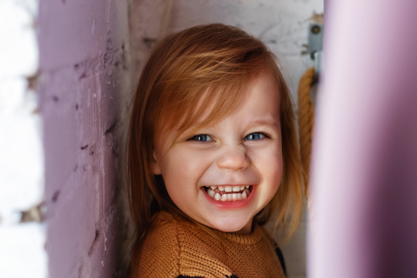 Una niña se esconde juguetonamente detrás de una cortina junto a la ventana. Juegos divertidos de esconder y buscar. - Foto, Imagen