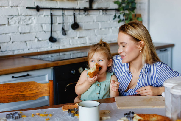Vicces kis baba segítő játszik tészta a kezét tanul gyúrni segít a felnőtt anya a konyhában, boldog aranyos baba lánya és a szülő anya szórakozni főzés cookie. - Fotó, kép
