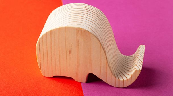 Elephant figurine carved from solid pine by hand jigsaw. On a multi-colored background. - Φωτογραφία, εικόνα