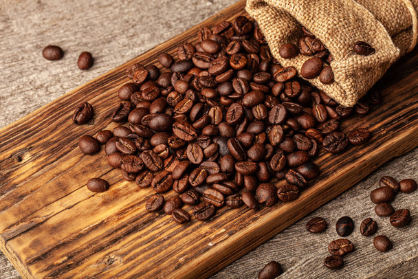 Roasted coffee beans on the old dark wooden background for wallpaper or decor. - Fotoğraf, Görsel