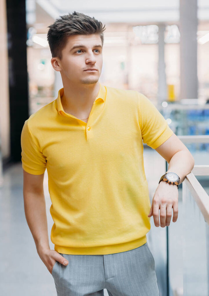 Modern businessman in yellow t-shirt standing in the business center - Фото, изображение